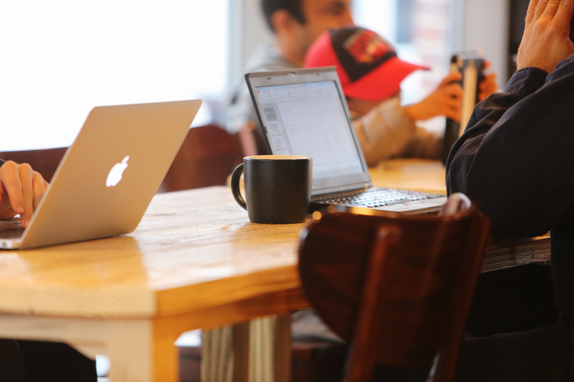 coffee mug next to two laptops